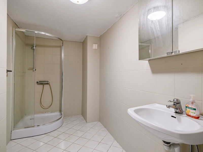 Badet har flislagt gulv med elektriske varmekabler, flislagte vegger og malt betonghimling.