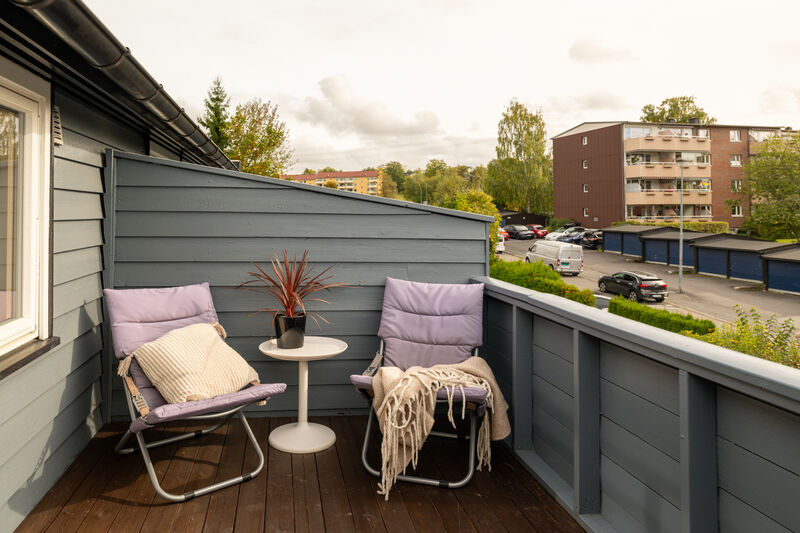 Balkongen har terrassebord på gulv og levegger/rekkverk av treverk. Det er også montert utebelysning.